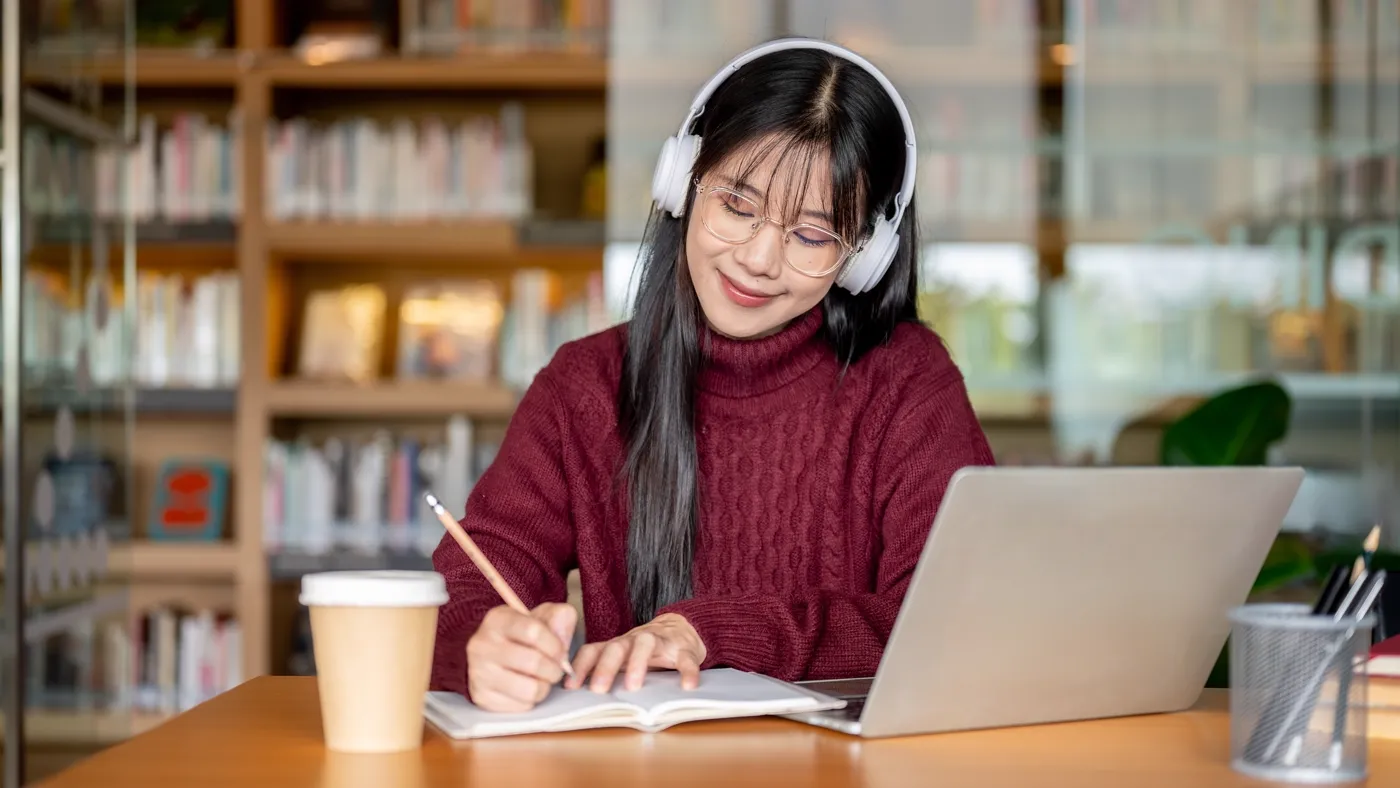 Student studying with headphones in a library