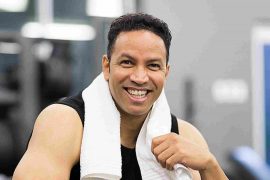 A fit man smiles after exercise, showcasing the benefits of a healthy lifestyle.