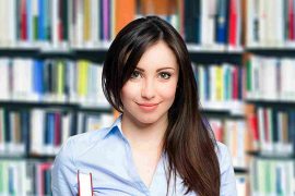 A smiling teacher holds books, representing English language learning at Common Wealth English.