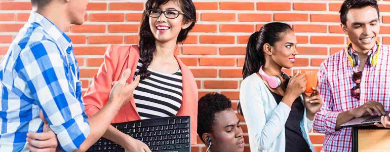Students collaborate using laptops in a classroom, representing next-gen higher education.