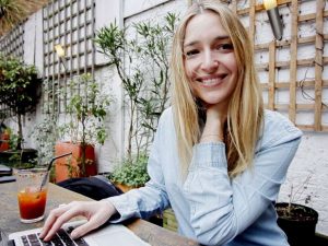 A woman enjoys English language learning on her laptop at a cafe.