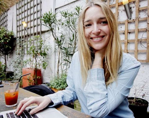A woman enjoys English language learning on her laptop at a cafe.