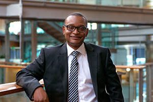 A business professional in glasses represents corporate partnerships for English language learning.