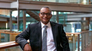 A business professional in glasses represents corporate partnerships for English language learning.