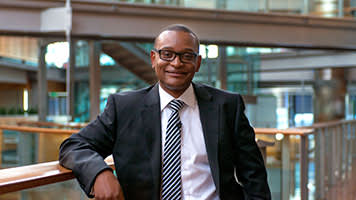 A business professional in glasses represents corporate partnerships for English language learning.