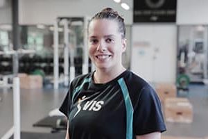 A woman weightlifts in a gym, demonstrating the benefits of Common Wealth English for athletes.