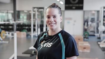 A woman weightlifts in a gym, demonstrating the benefits of Common Wealth English for athletes.
